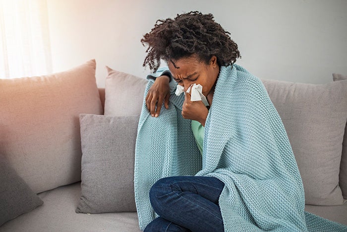 woman on sofa with tissue and blanket