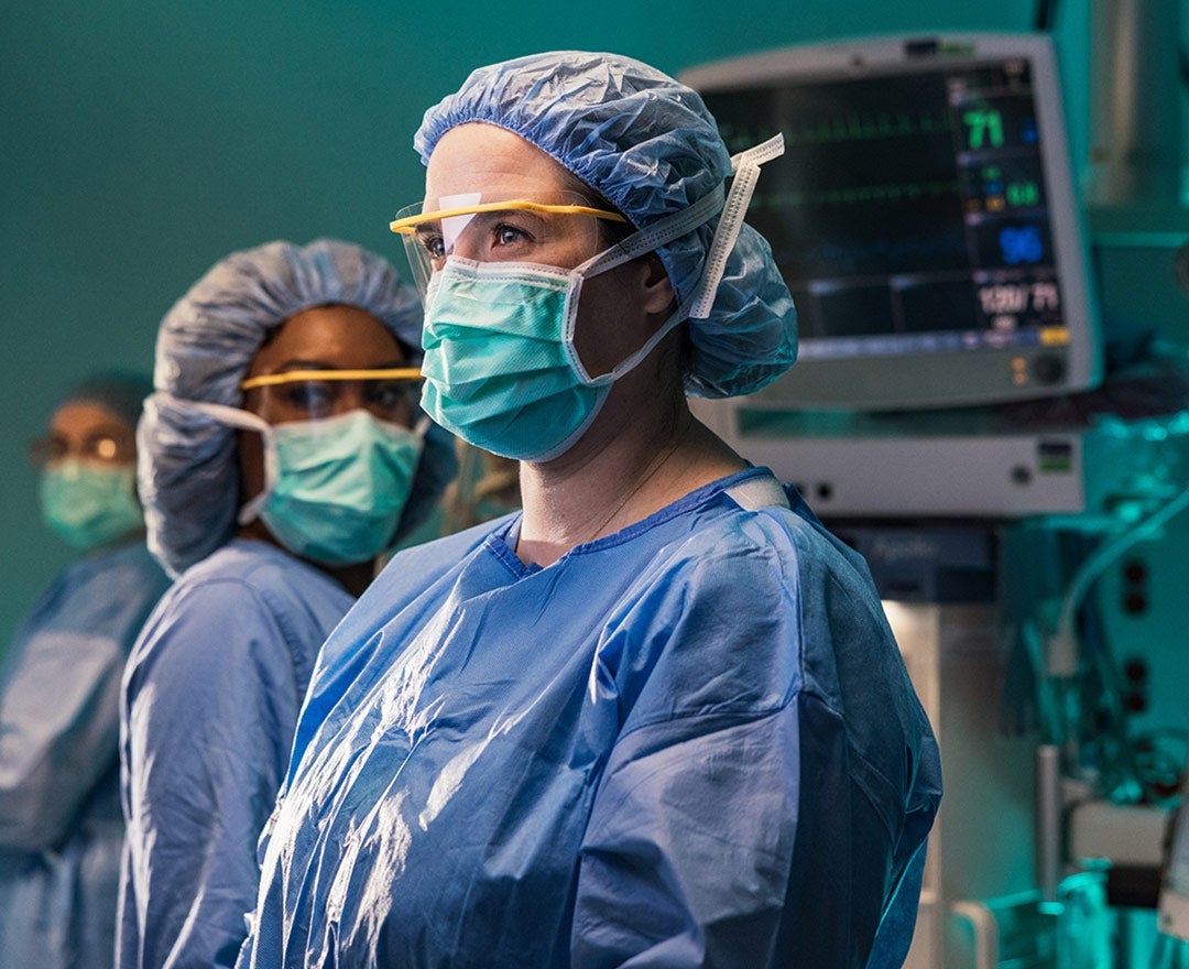 Close shot of Dr. Belfield, a general surgeon fellowship-trained in minimally invasive surgery, looking up in full PPE in the OR.