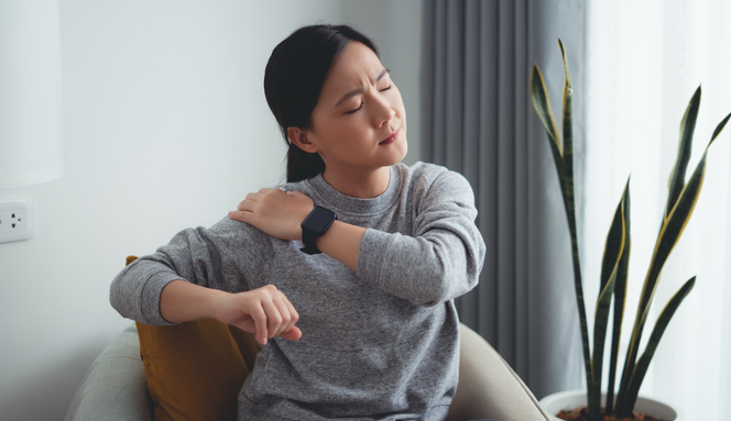 young woman holding her shoulder in pain