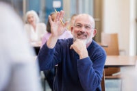 Senior man raising his hand to ask a question at an educational event